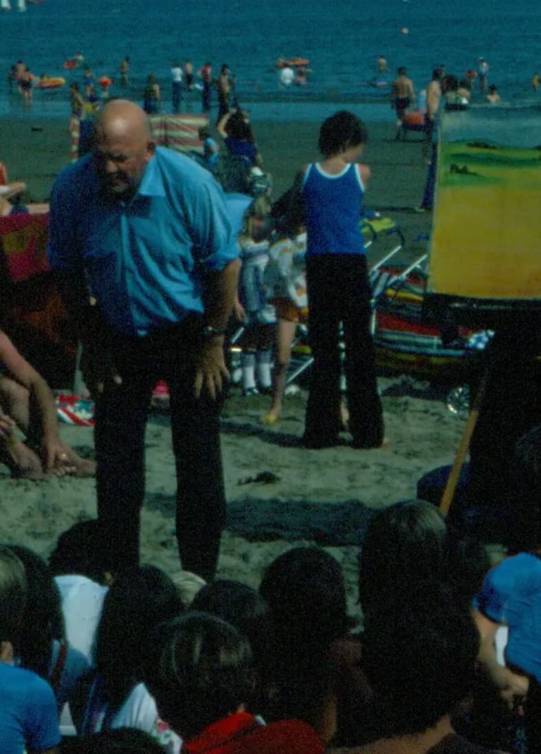 Image of a packed beach with a guy from the beach mission team telling a story