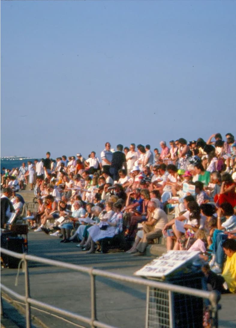 Image of crowds of people sitting on the beach steps having an outdoor church service