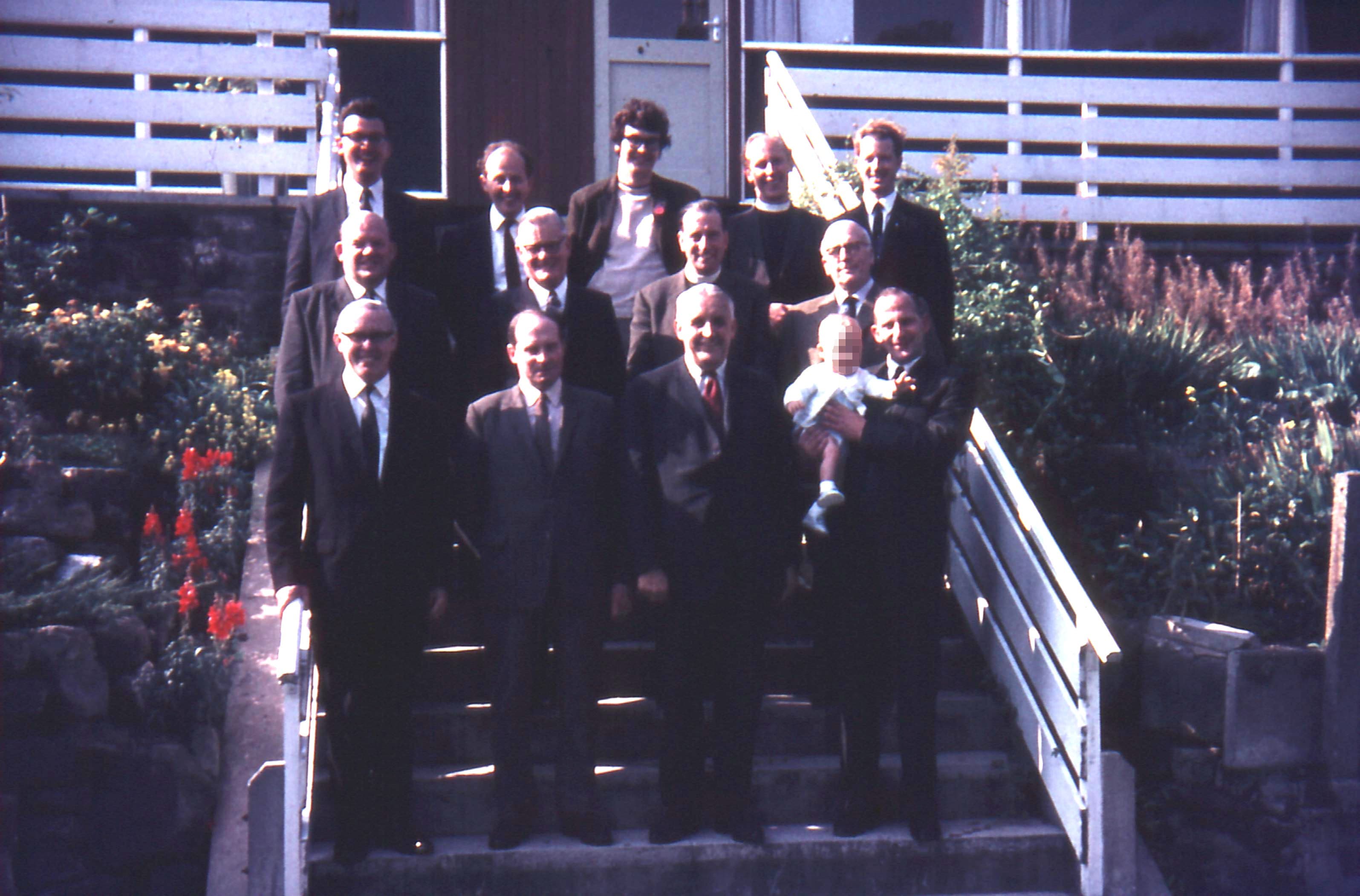 Image of 13 of the Emmanuel Holiness Ministers standing on the steps leadign up to Drysdale Hall